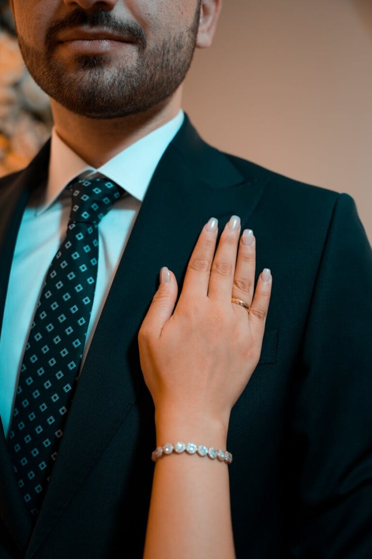 Close-up of a couple showcasing a diamond bracelet and suit in an elegant setting.