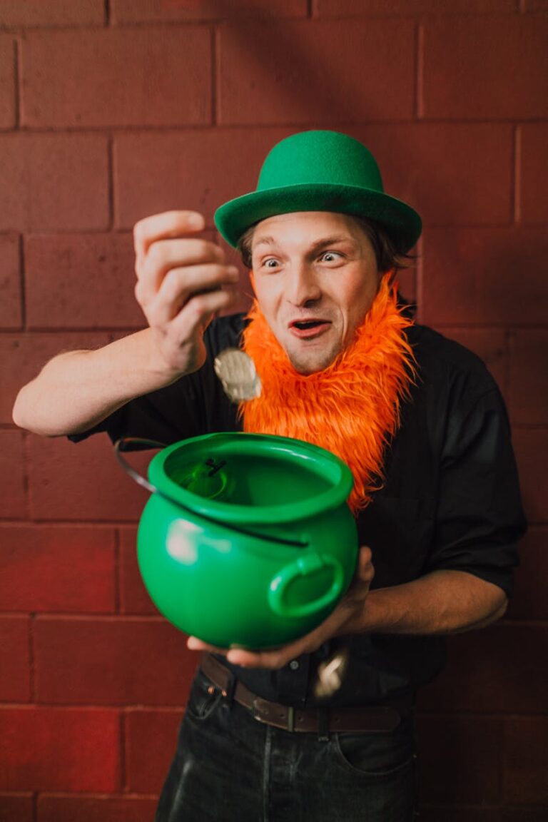 Man in leprechaun costume holding a green pot indoors, celebrating St. Patrick's Day.