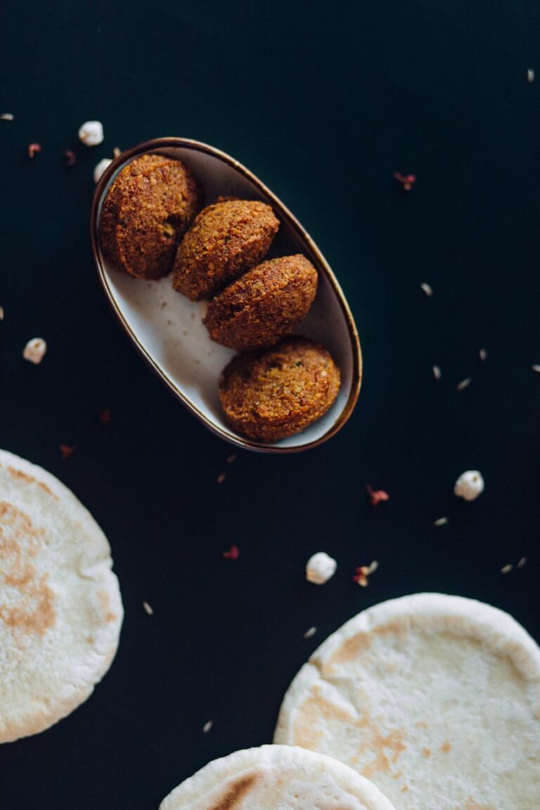 Close-up shot of crispy falafel served with fresh pita bread on a dark background.