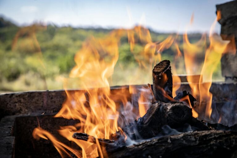 A close-up of a vibrant bonfire outdoors with blazing flames and smoldering wood.