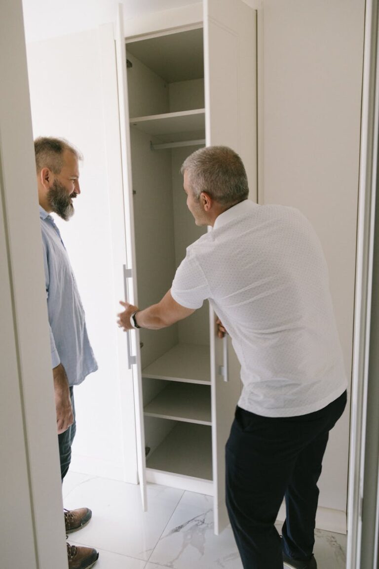 Two men examining and discussing the design of a built-in wardrobe in an interior space.