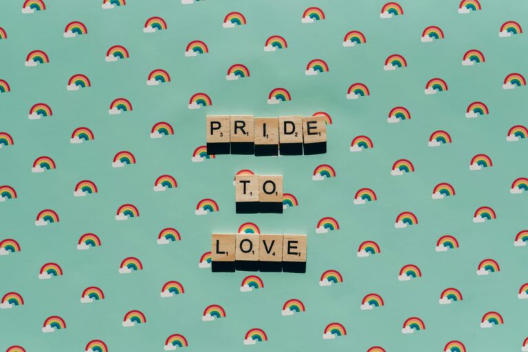 Scrabble tiles spelling 'Pride to Love' on a rainbow background, celebrating LGBT pride.