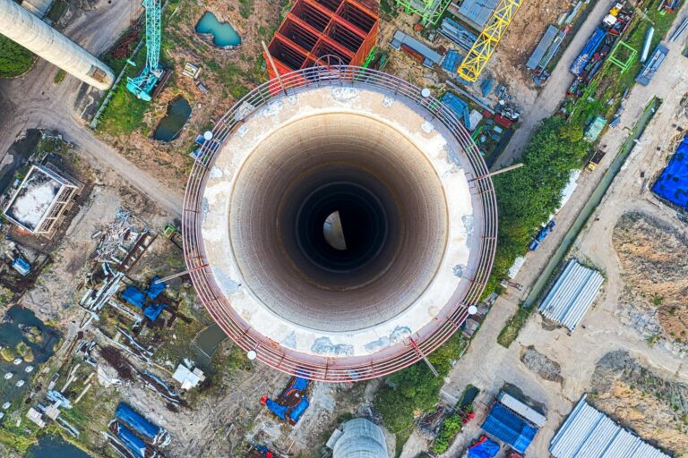 Aerial perspective of a cooling tower in an industrial area, highlighting complex machinery and structures.