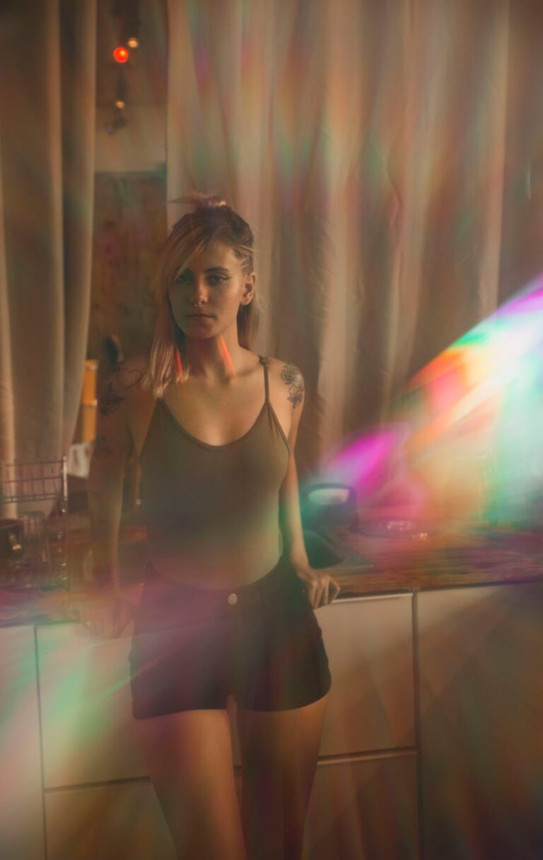 Woman standing indoors with a vibrant prism effect creating colorful light reflections.