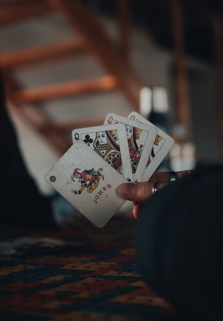 Close-up of a hand holding a set of playing cards, creating a moody atmosphere.