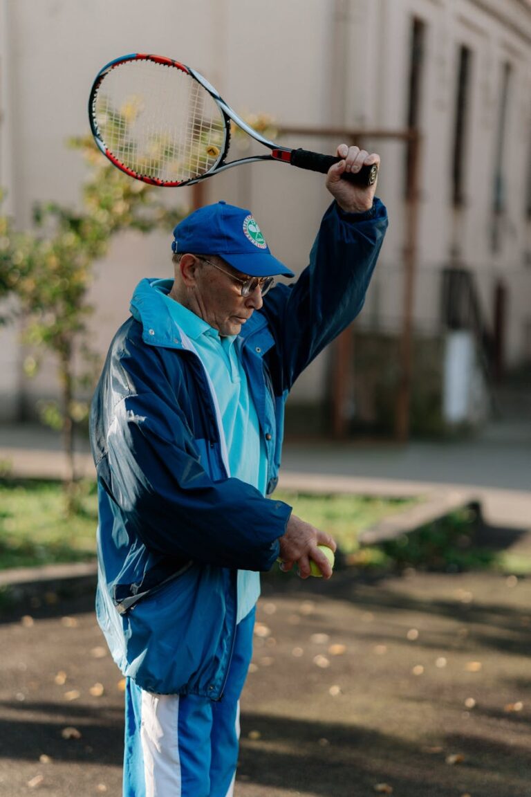 Senior man in sportswear practicing tennis swing outdoors. Active lifestyle.