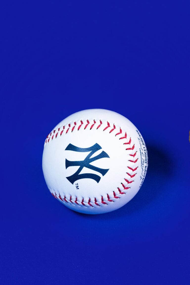 Close-up of a baseball with Yankees logo on vibrant blue background.