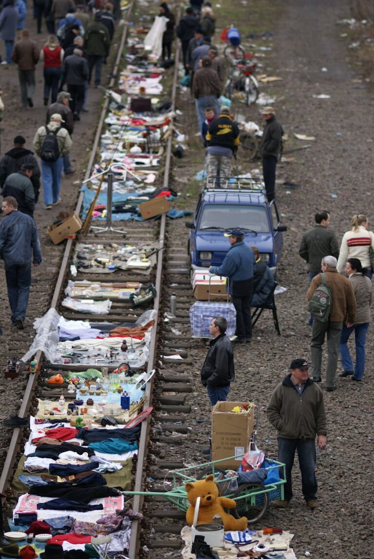 A bustling outdoor market set along railway tracks in Wrocław, Poland.