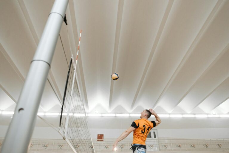 Male volleyball player jumps to spike the ball during an intense indoor game.