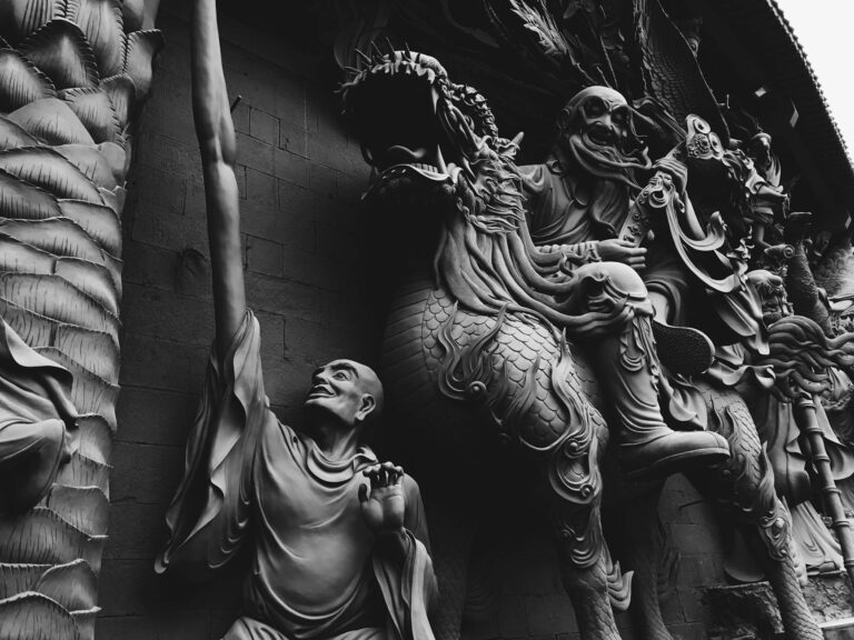 Black and white close-up of detailed religious sculptures with a dramatic tone.