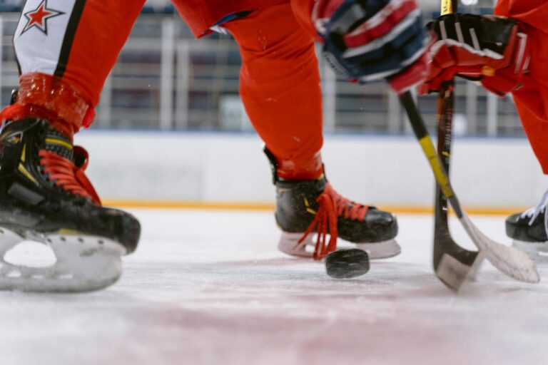 Dynamic close-up of ice hockey players competing for puck control during a face-off.