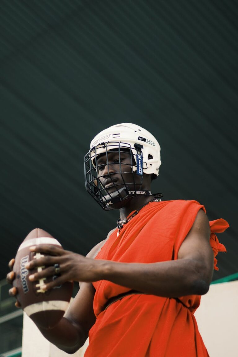 African athlete in traditional attire with helmet and football, blending cultures.