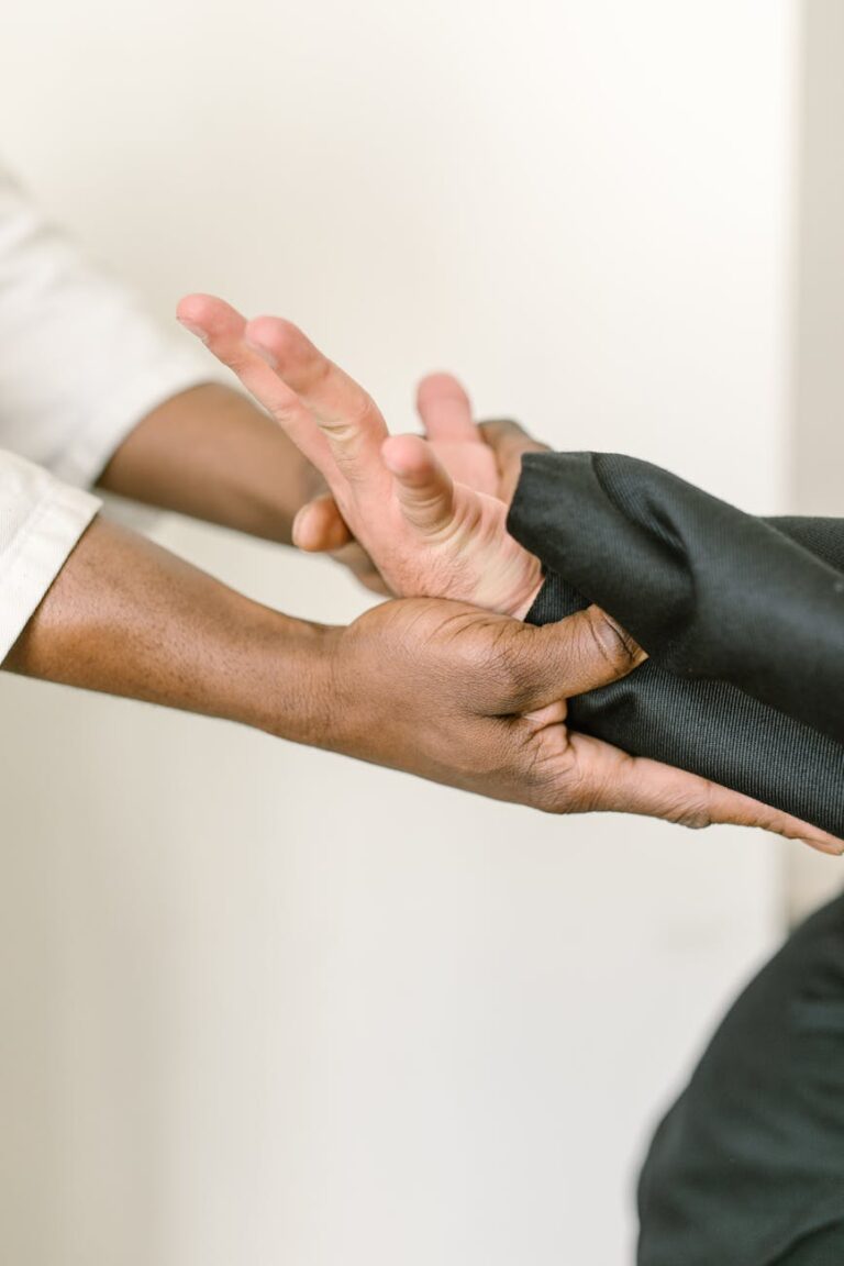 Close-up of two people practicing martial arts hand technique indoors, demonstrating cooperation and skill.