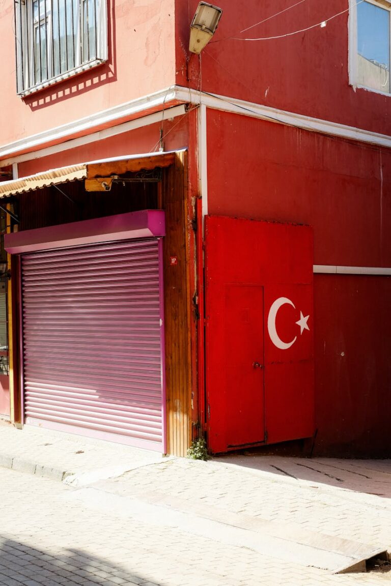 A closed garage door next to a red wall adorned with the Turkish flag, captured on a sunny day.