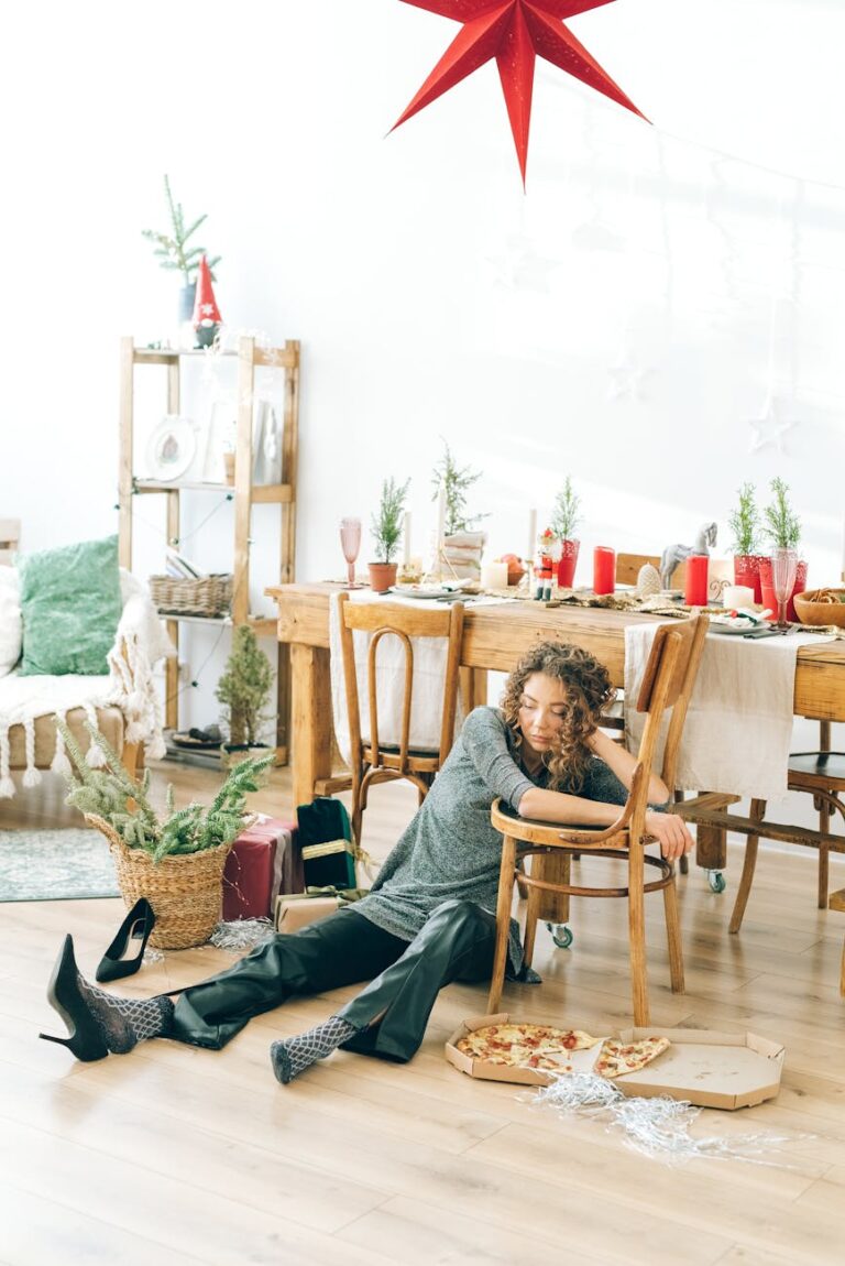 A woman rests on a dining chair in a festive indoor setting with pizza and decorations.