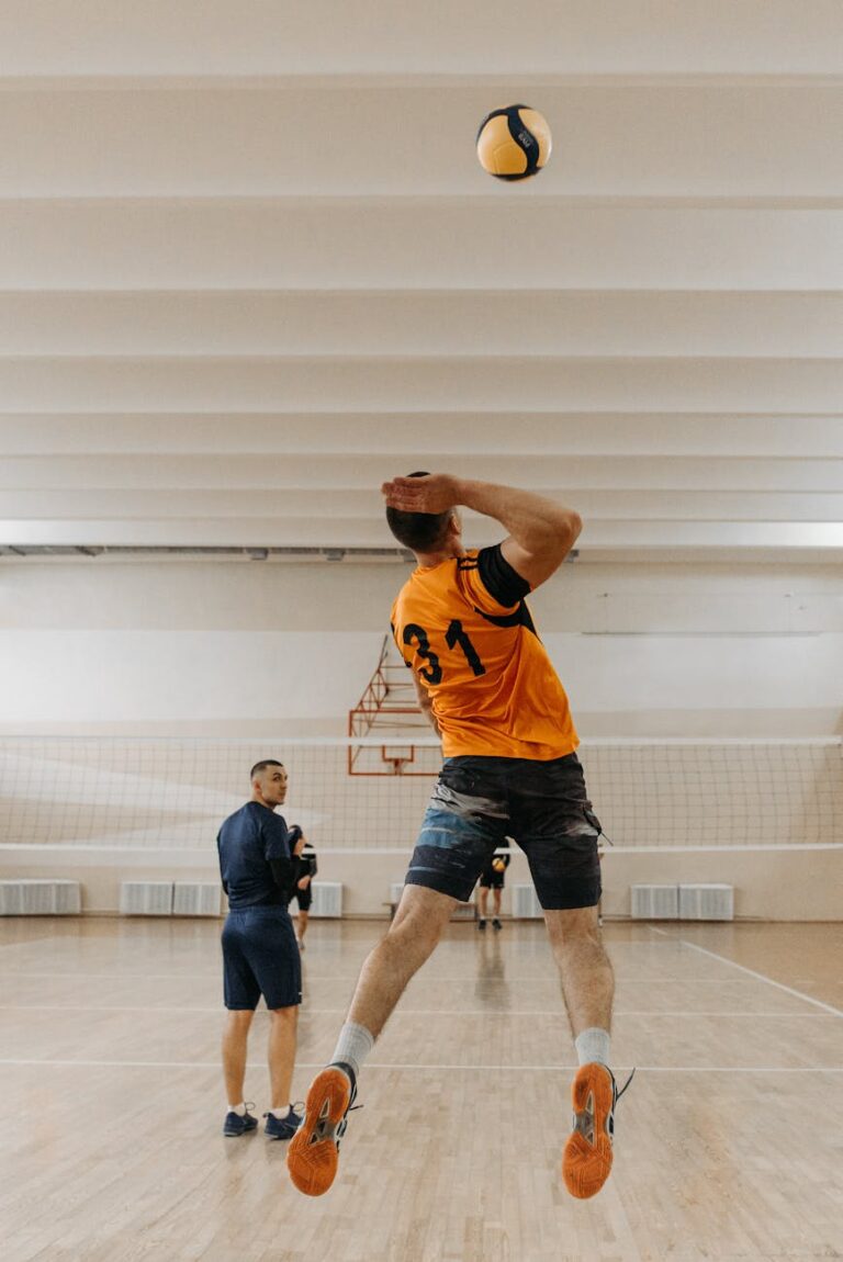 Athlete jumps to serve volleyball during an indoor practice session.