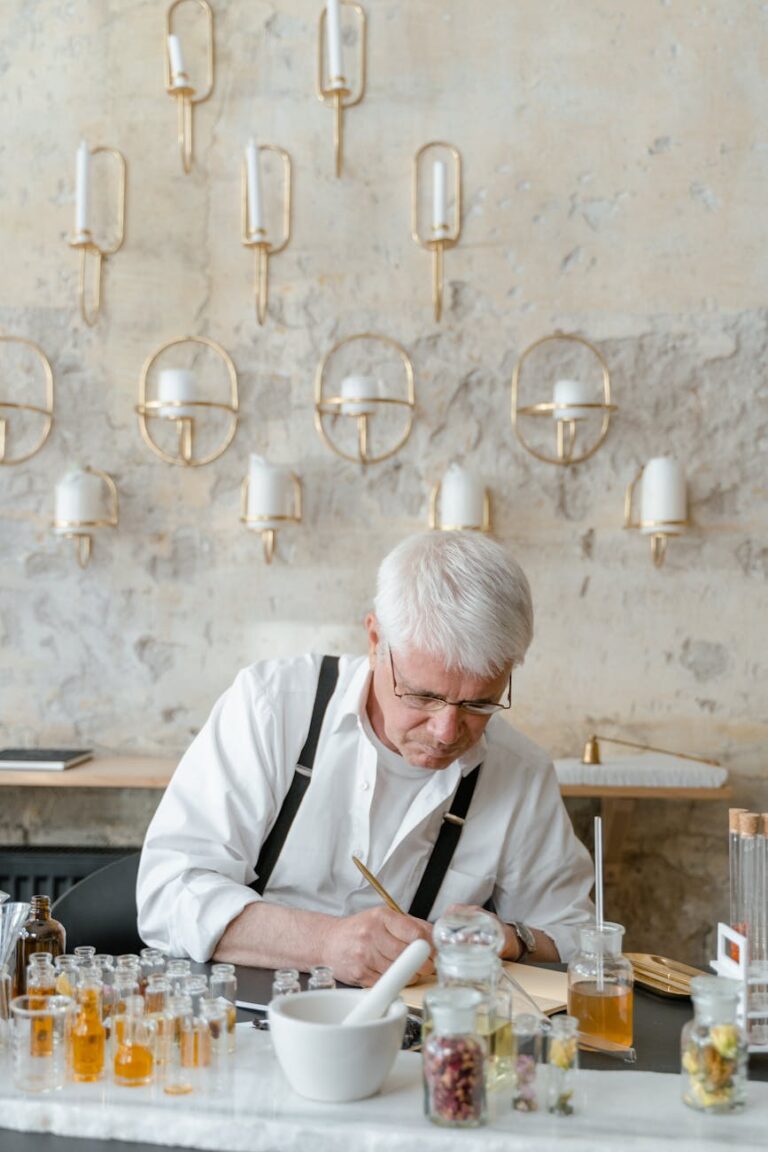 Senior man engaged in creating natural skincare products using essential oils in a modern interior setting.