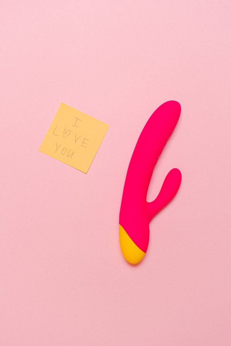 Modern pink vibrator accompanied by a playful 'I love you' note on a soft pastel backdrop.
