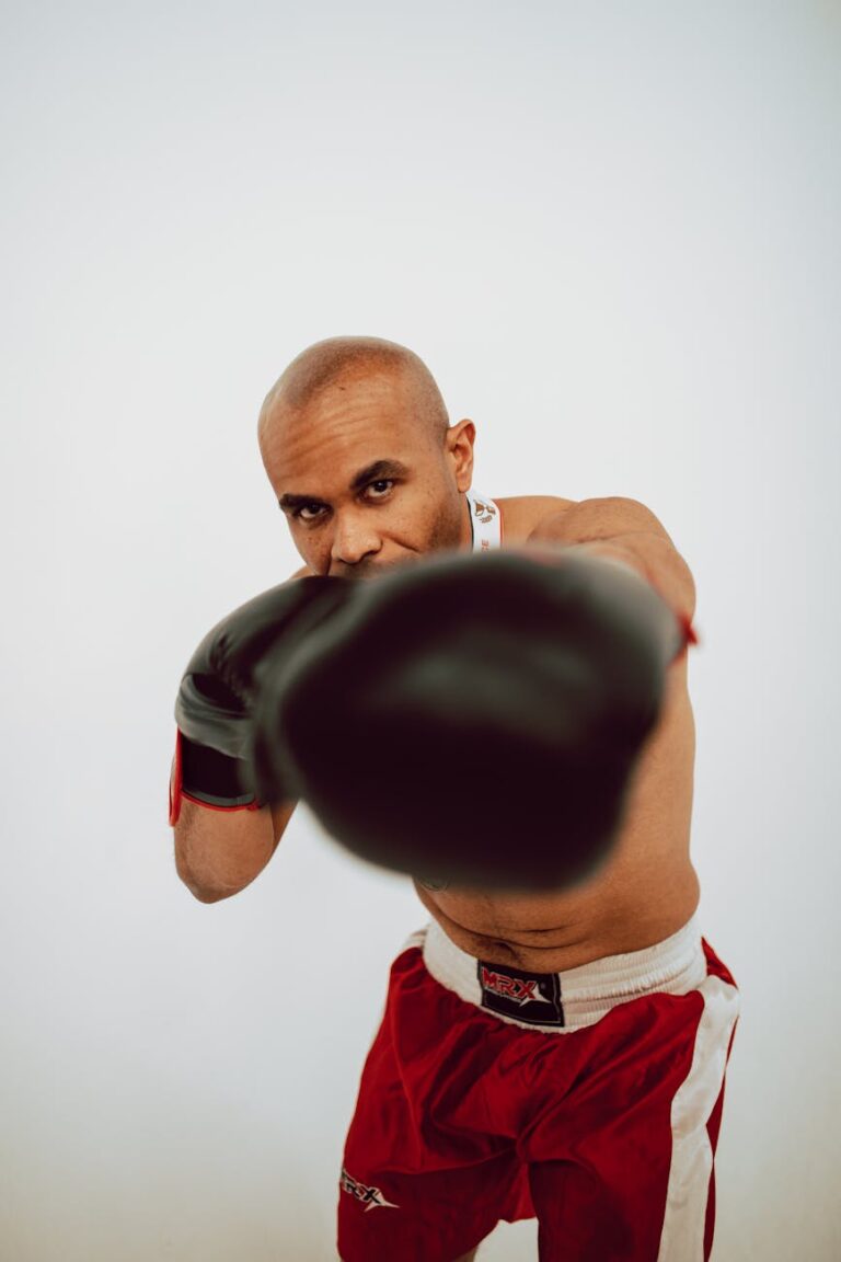Focused boxer in red shorts delivering a strong punch towards the camera.
