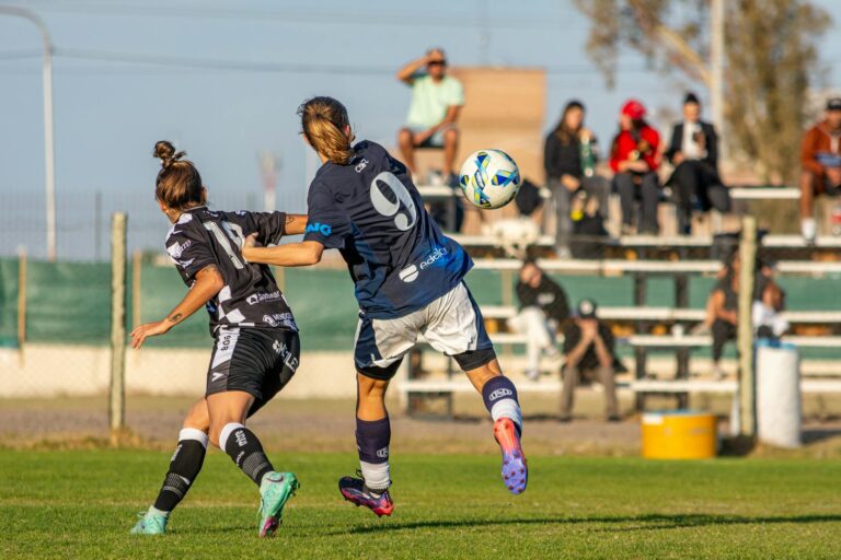 Two female soccer players in action during a competitive outdoor football match. Energetic sports scene.