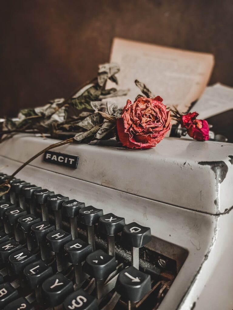 Close-up of a vintage typewriter adorned with withered roses, evoking a nostalgic mood.