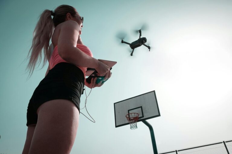 A woman operates a drone near a basketball court, capturing an aerial view in Dubai.