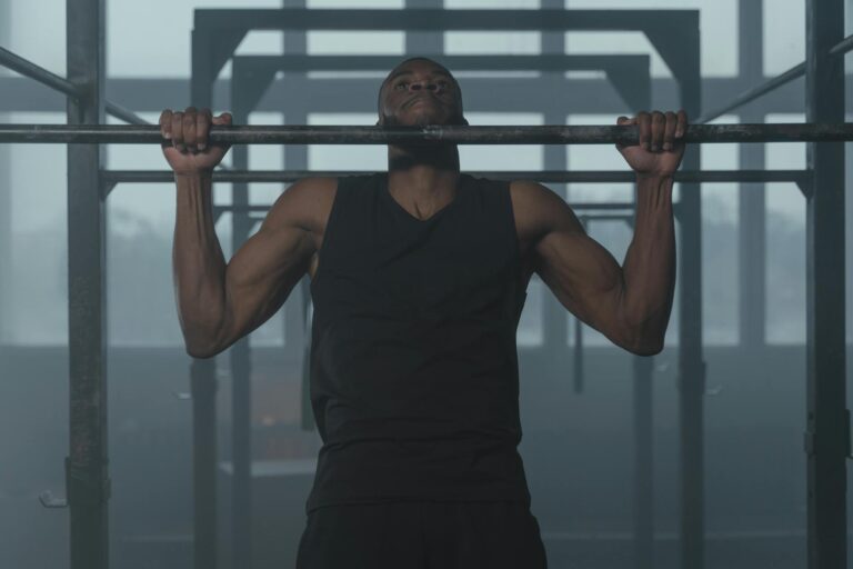 An African American man doing pull-ups in a gym, showcasing strength and fitness.