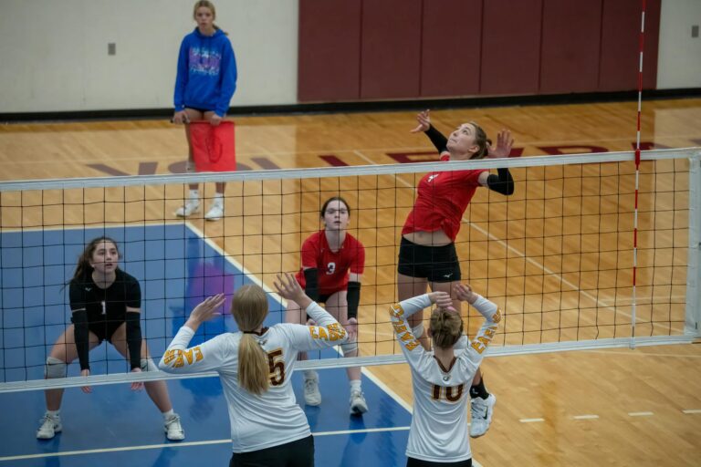 Women athletes playing competitive volleyball indoors at Rochester, MN court.
