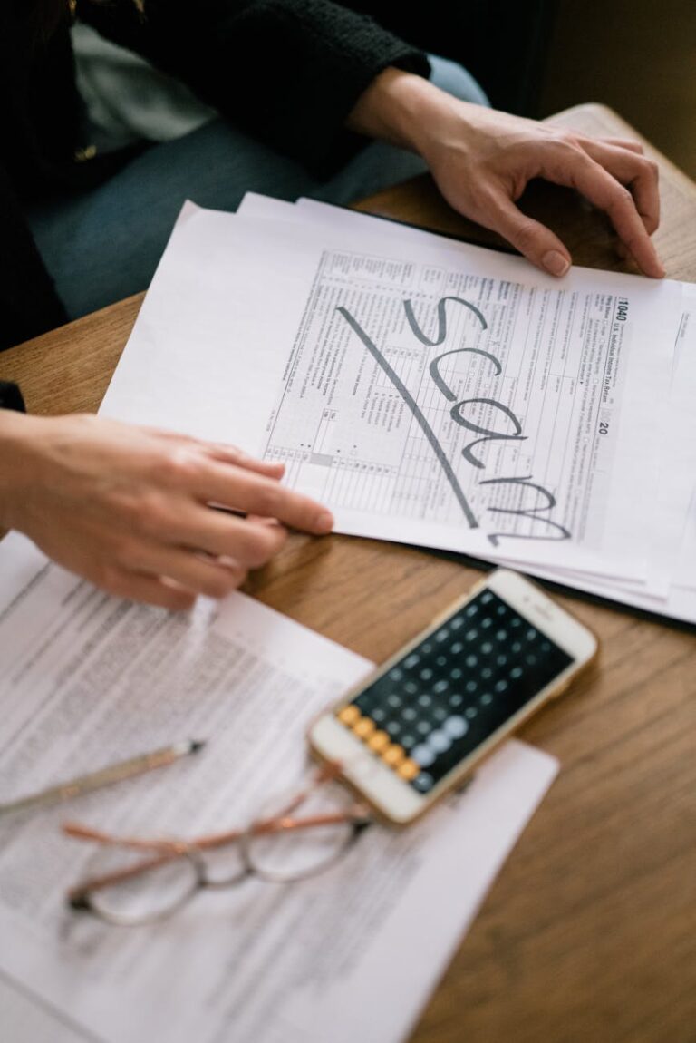 Close-up of hands examining documents marked 'scam' with a calculator nearby.