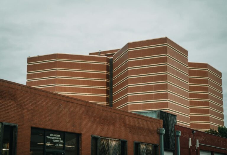 A perspective view of modern brick buildings with horizontal patterns under a cloudy sky.