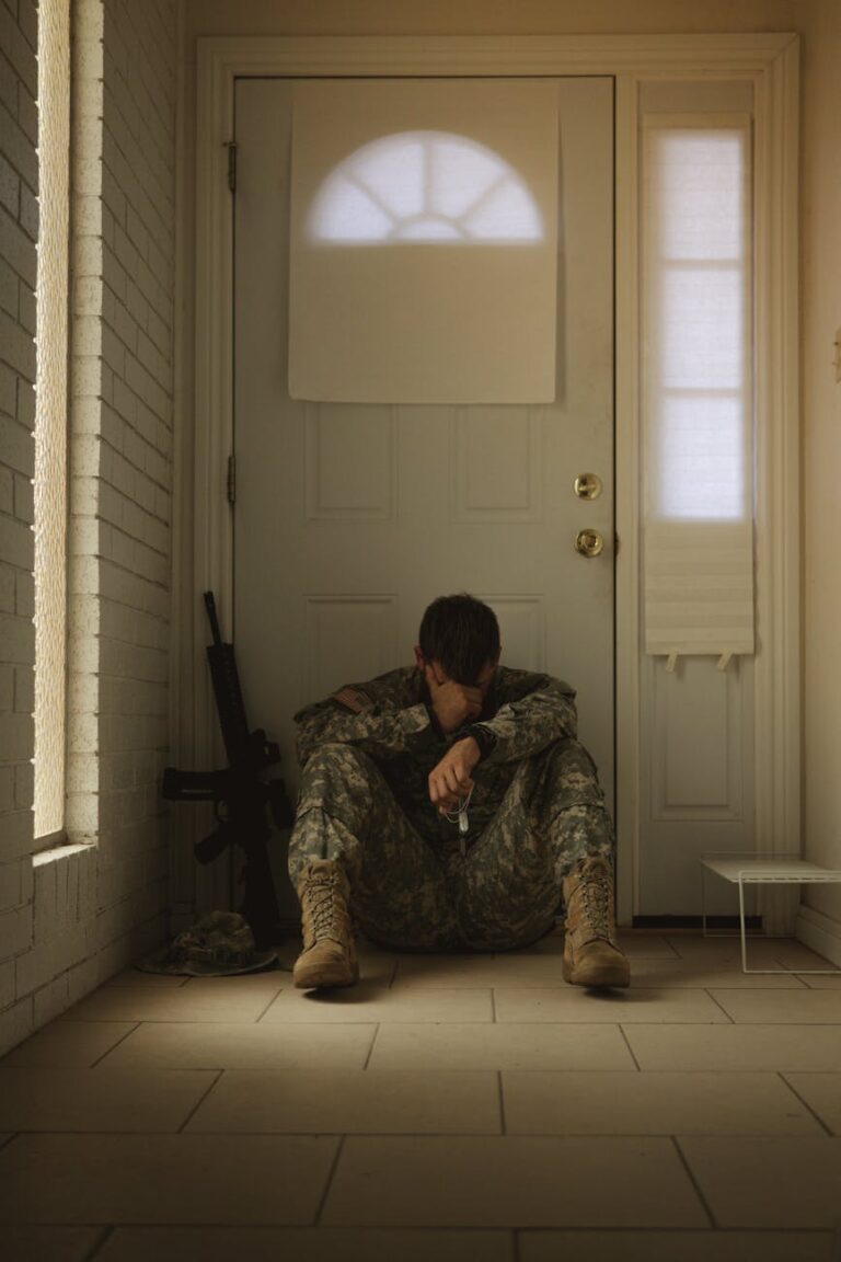 A solitary soldier in uniform sitting by a door, reflecting mood.