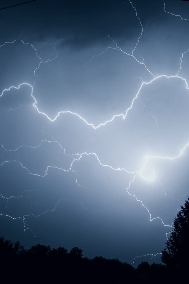 A dramatic sky illuminated by vibrant lightning during a nighttime thunderstorm.