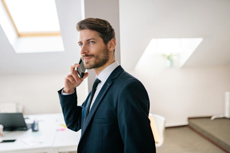 Professional businessman in a suit making a phone call in a modern office setting.