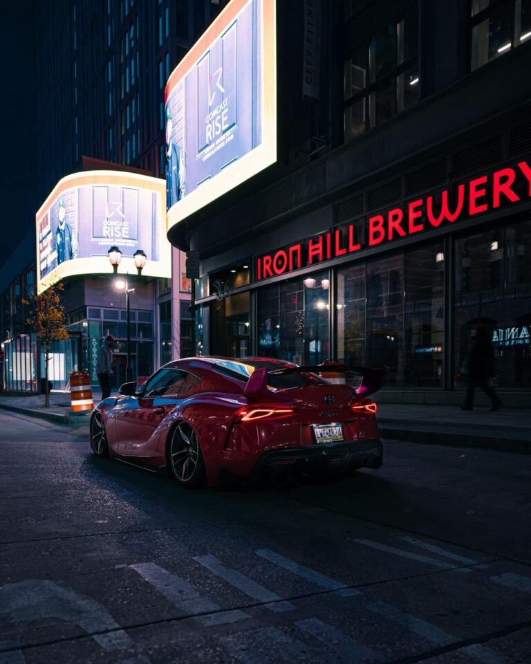 A vibrant red sports car parked near Iron Hill Brewery, Philadelphia at night.