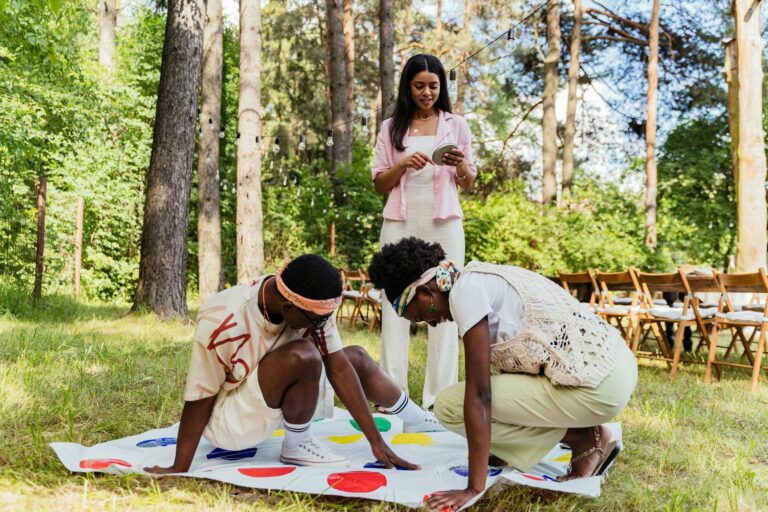 Group of young adults enjoying a playful Twister game in a sunny park setting.