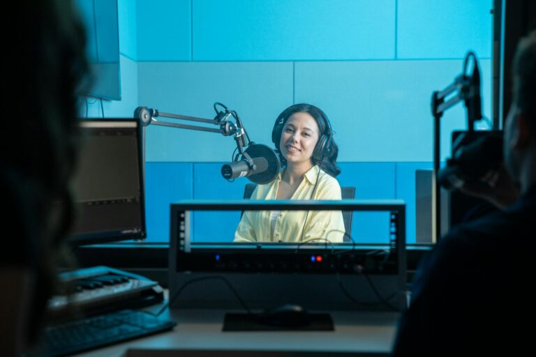 A podcast host records a show in a professional radio studio with microphones and headphones.