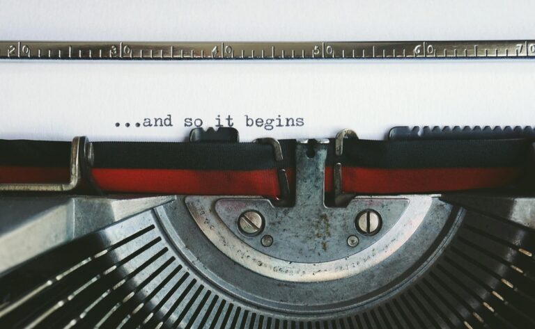 Close-up of a vintage typewriter with the quote '...and so it begins'.