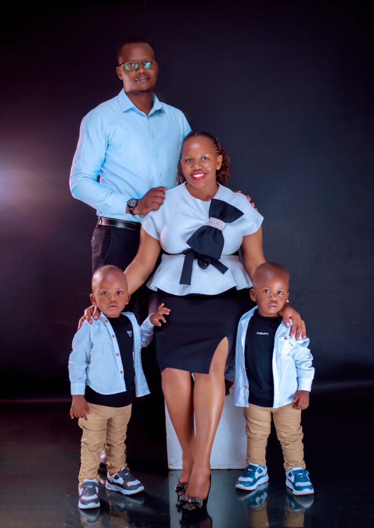A family of four posing elegantly in coordinated formal attire in a studio setting.