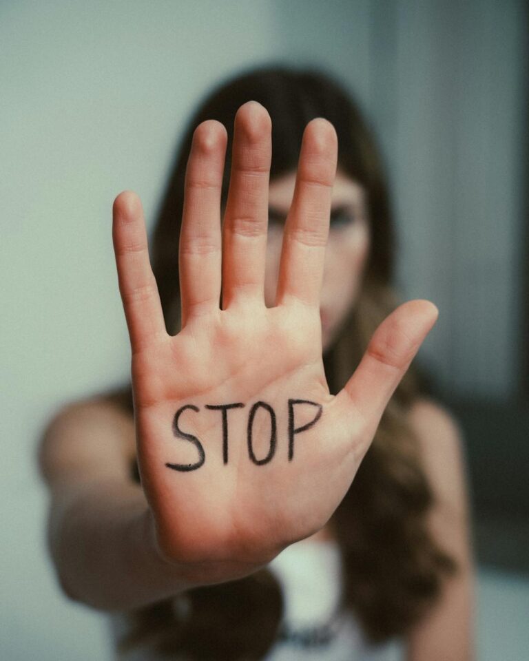 Close-up of a woman's hand with 'Stop' written on it, emphasizing awareness.