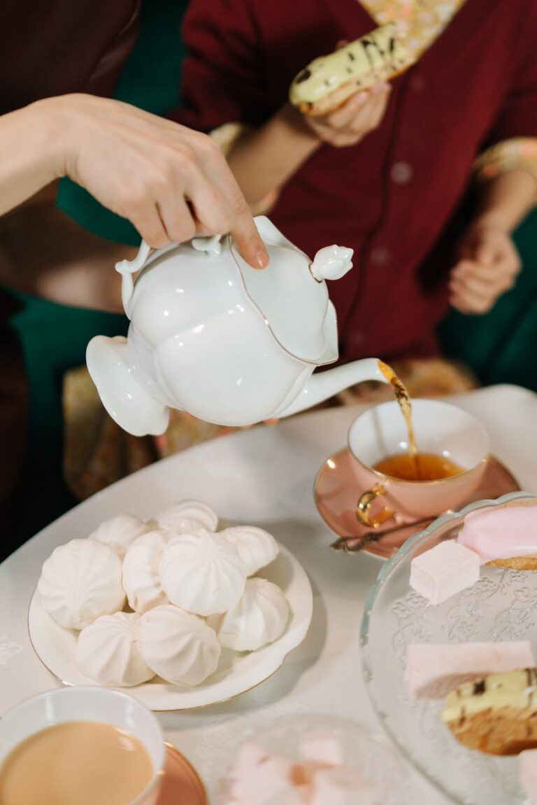 A classic tea pouring scene with meringues and pastries, perfect for lifestyle concepts.