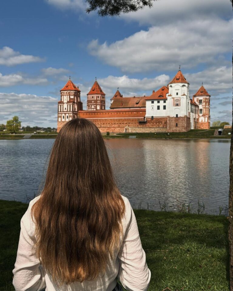 Woman gazing at the historic Mir Castle in Belarus on a sunny day.