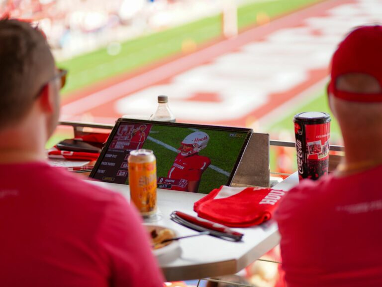 Fans enjoying a live football game on a tablet at a stadium in Houston.