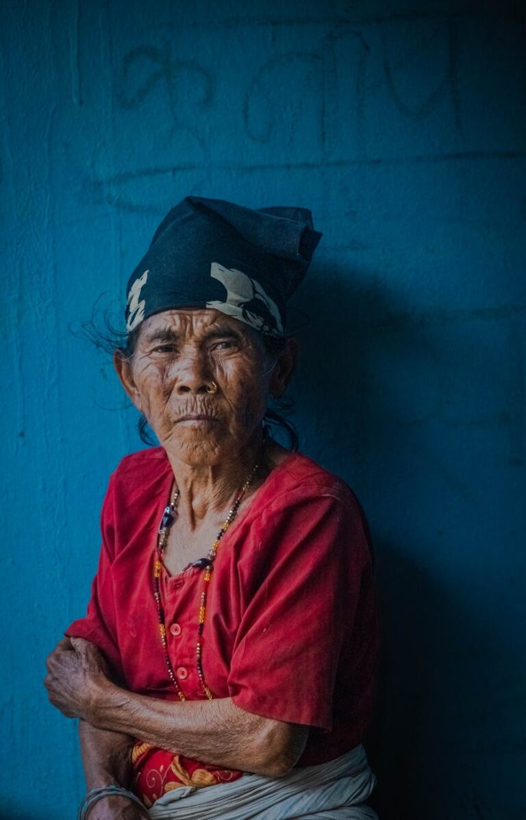Elderly woman with headscarf and necklace, showcasing tradition and age in a vibrant, moody portrait.