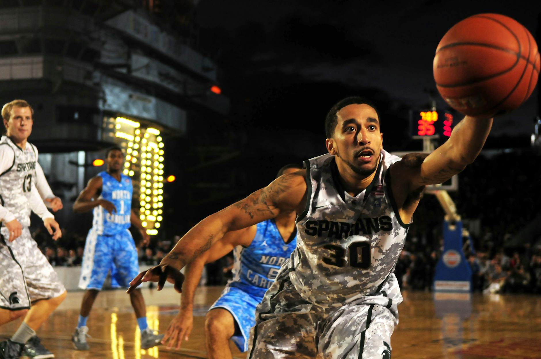 Intense basketball game with athletes in action on an outdoor court during nighttime.