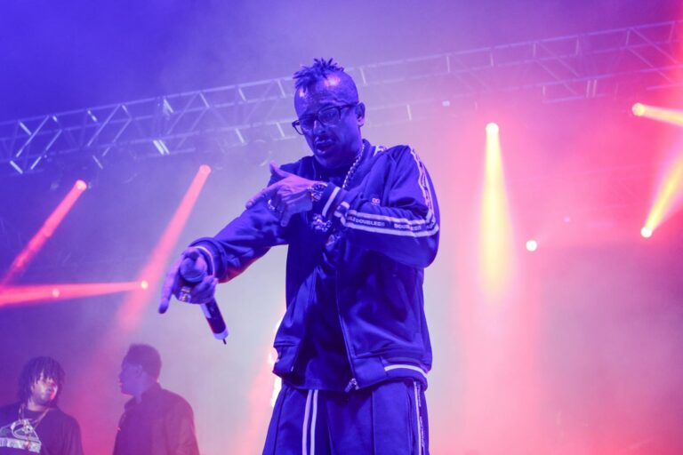 Vibrant live rap concert with performer on stage under colorful lights.