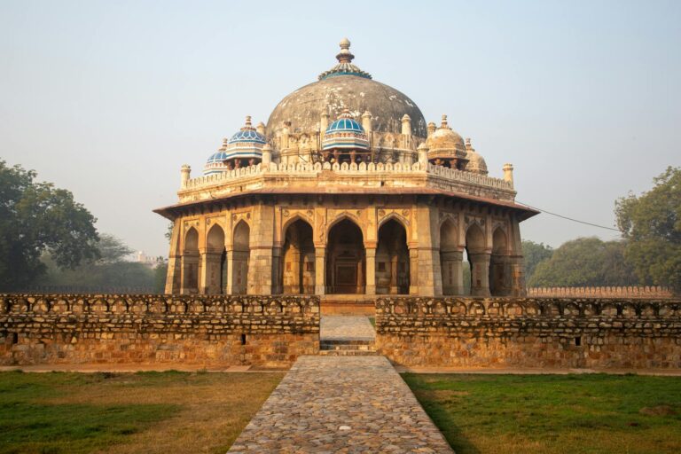 Stunning view of an ancient tomb in Delhi featuring intricate arches and a prominent dome, set in a historical landscape.
