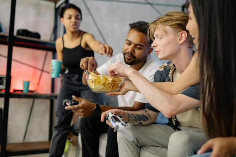 A group of friends enjoy snacks and gaming indoors, showcasing leisure and diversity.