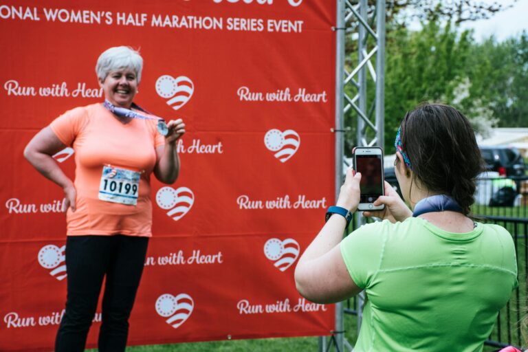 Woman proudly shows medal after completing women's half marathon, captured for memories.