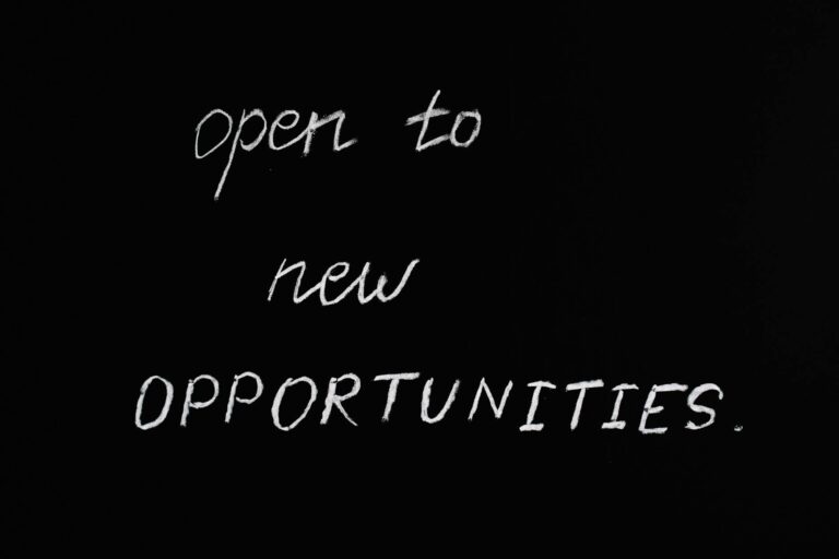 Blackboard with motivational quote 'Open to New Opportunities' in chalk writing.
