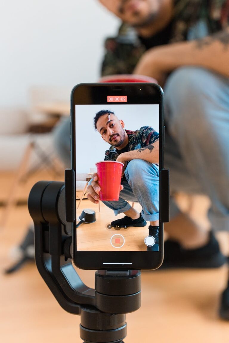 Man records a red cup trick using a smartphone mounted on a tripod.